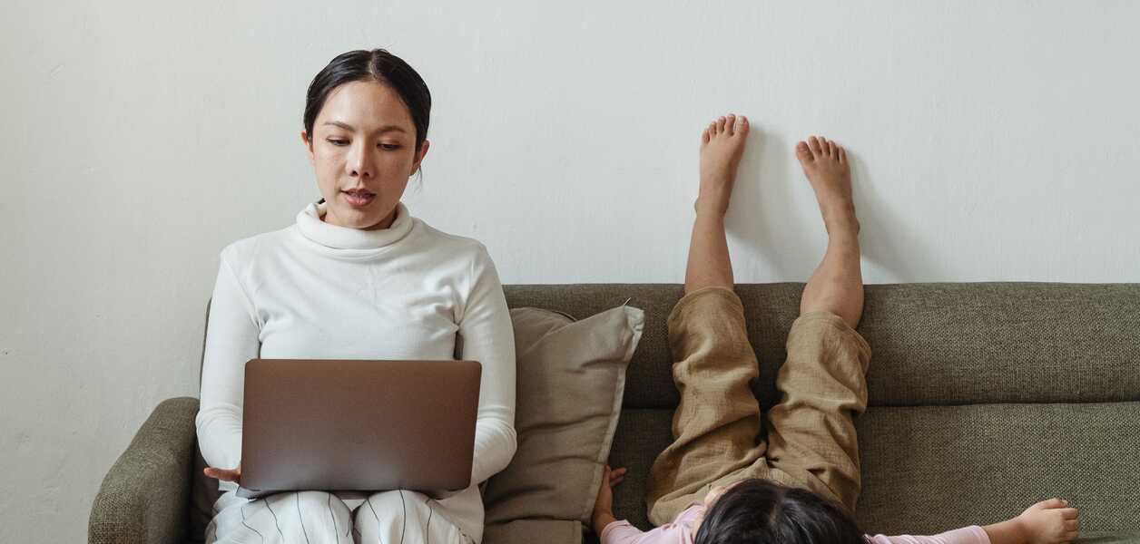 Woman working on couch next to daughter