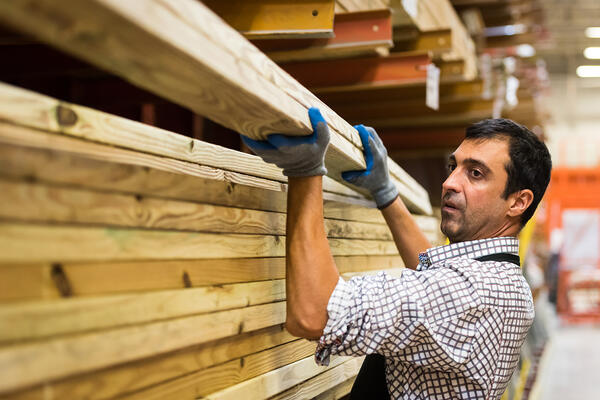 Man working at home improvement place carrying lumber