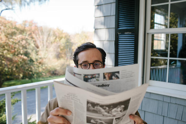 Man reading newspaper outside