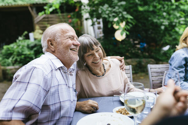 Senior man and woman smiling and hugging during a meal