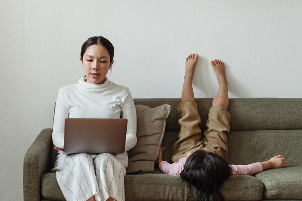Woman working on couch next to daughter