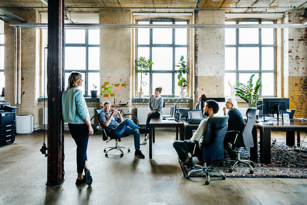 Coworkers all chatting in open concept office 