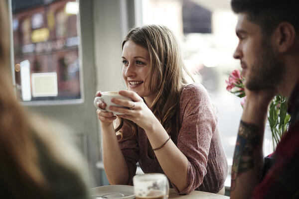 People sitting at a table while smiling and drinking coffee