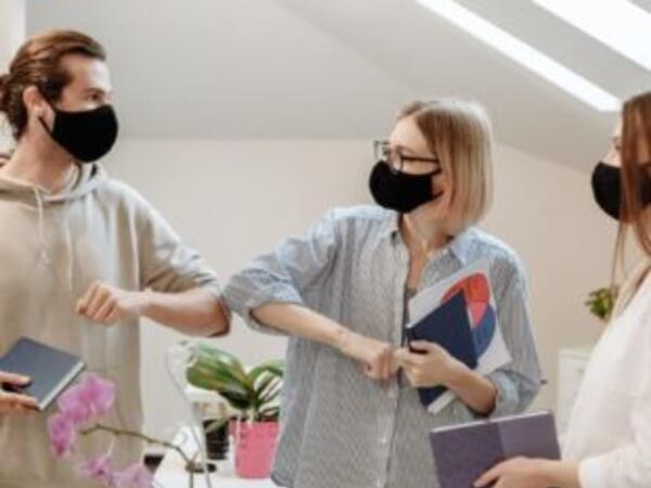 Coworkers elbow bumping with masks on