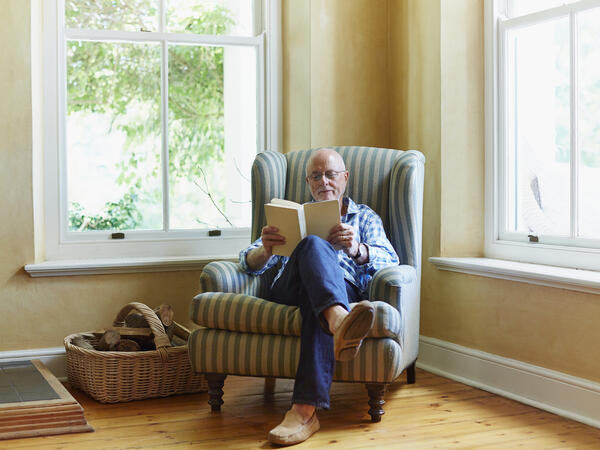 Man sitting in living room chair reading a book