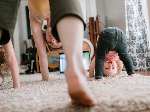 Mother and children doing downward dogs in the living room